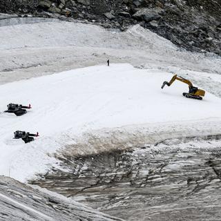 Les pelleteuses creusent le glacier Théodule pour créer une piste de ski alpin pour la Coupe du monde. [Keystone - Jean-Christophe Bott]