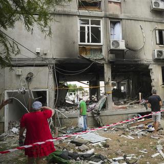 Des Israéliens inspectent un immeuble résidentiel endommagé par une roquette tirée depuis la bande de Gaza, à Ashkelon, Israël, lundi 9 octobre 2023. [KEYSTONE - ERIK MARMOR]