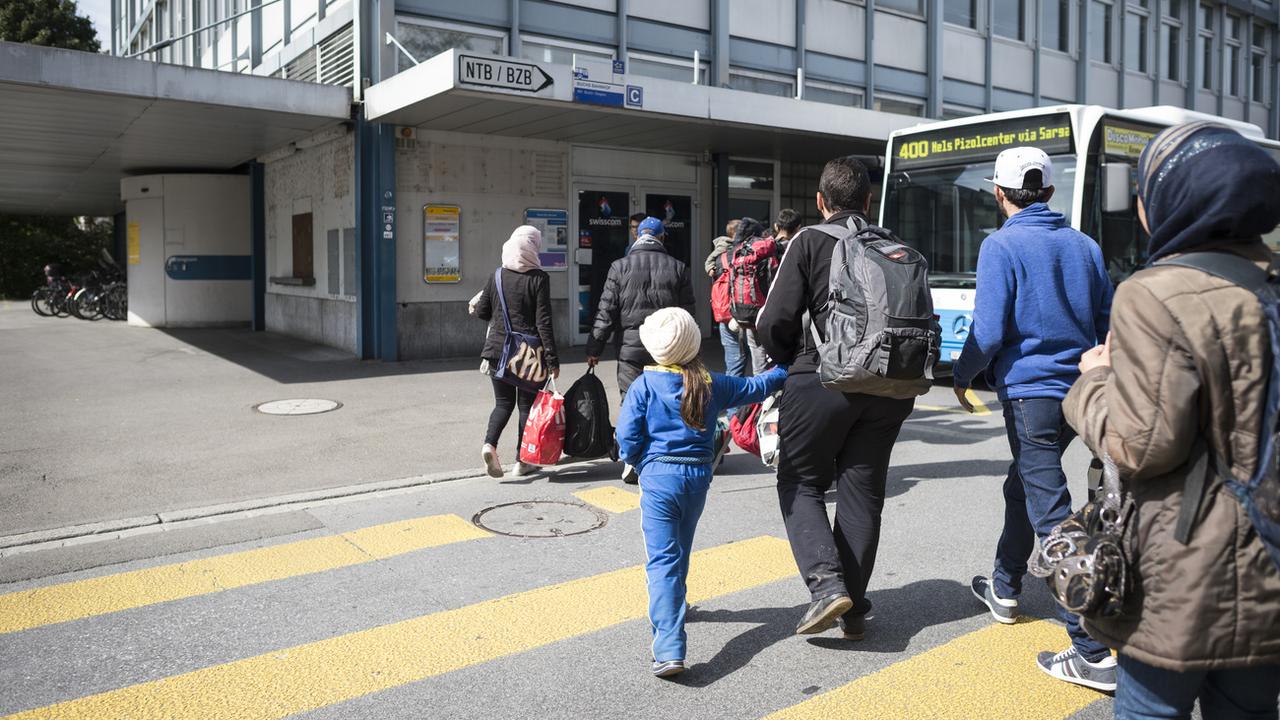 Des personnes migrantes quittent la gare de Buchs pour gagner un poste de police. [Keystone - Gian Ehrenzeller]