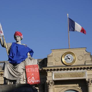 La statue de la loi est habillée d'un poster demandant la retraite à 60 ans, en marge de la grève contre l'élévation de la retraite en France. [Keystone/AP Photo - Christophe Ena]