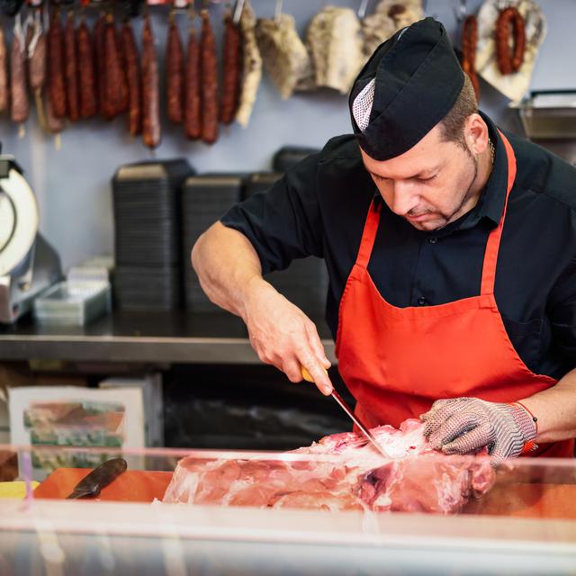 Un boucher désosse un jambon. [Depositphotos - Mavoimages]