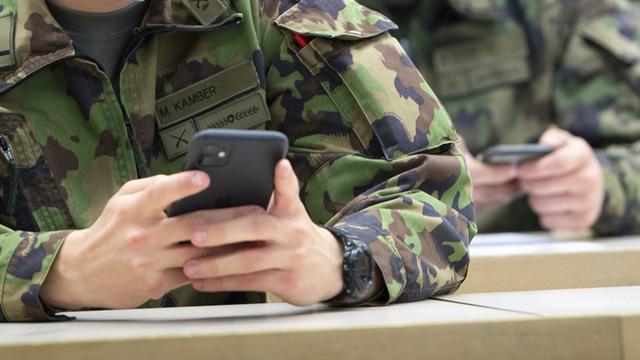 Des recrues de l'armée suisse devant leur téléphone. [Keystone - Laurent Gillieron]