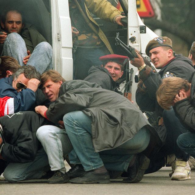 Un soldat des forces spéciales bosniaques riposte, le 6 avril 1992, dans le centre de Sarajevo alors que lui-même et des civils sont pris pour cibles par des tireurs d'élite serbes. Ceux-ci tiraient depuis le toit d'un hôtel sur une manifestation pour la paix réunissant quelque 3'000 personnes, alors que les combats entre combattants bosniaques et serbes s'intensifiaient dans la capitale de la Bosnie-Herzégovine. [Keystone/EPA - Mike Persson]