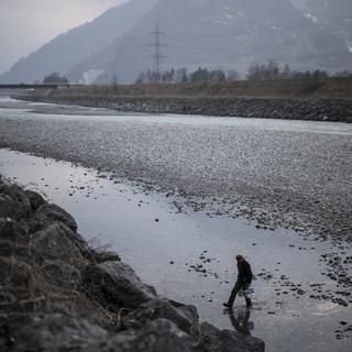 Un homme marche sur le Rhin en pleine sécheresse. [Keystone - Gian Ehrenzeller]