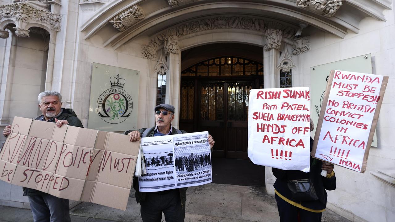 Des manifestants brandissent des pancartes pour protester contre la politique du gouvernement consistant à expulser les demandeurs d'asile vers le Rwanda, devant la Cour suprême du Royaume-Uni à Londres, Grande-Bretagne, le 15 novembre 2023. [Keystone - EPA/NEIL HALL]