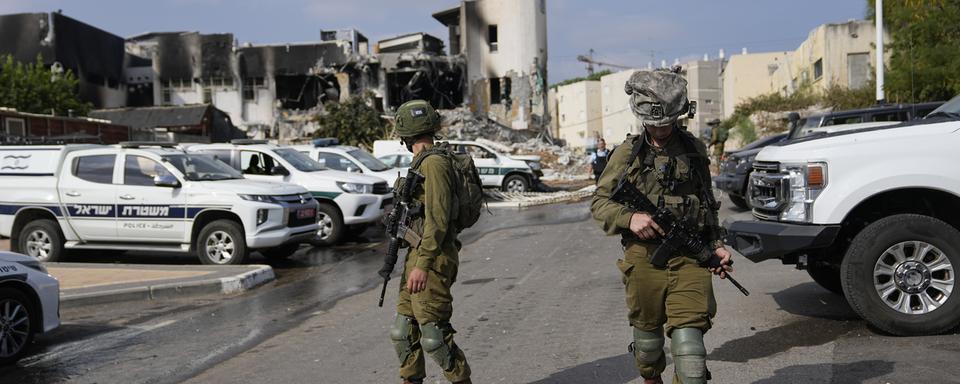 Des soldats israéliens marchent près du poste de police qui a été envahi par des militants du Hamas samedi, à Sderot, Israël, dimanche 8 octobre 2023. [Keystone - AP Photo/Ohad Zwigenberg]