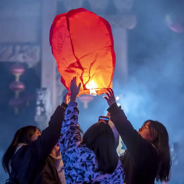 Des chinois font s'envoler une lanterne pour faire un voeux pour la nouvelle année. [EPA/XINHUA/Keystone - Fan Hui CHINA OUT]