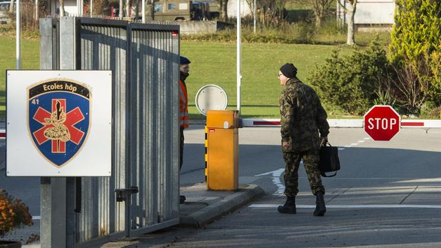 Un militaire approche de la caserne de Moudon, qui accueille désormais des requérents d'asile. [Keystone - Jean-Christophe Bott]