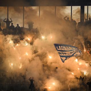 Les supporters lausannois allument des fumigènes lors de la rencontre en FC Lausanne-Sport et Neuchâtel Xamax FCS, le 12 mai 2023. [Keystone - Jean- Christophe Bott]