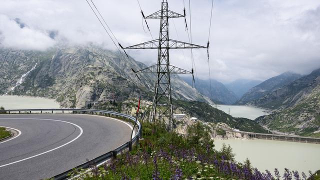 Des lignes électriques passent en aval des deux lacs de retenue du Grimsel, à l'avant, et du Raetterichs Boden, le mercredi 27 juillet 2022, au Grimsel. [Keystone - Peter Schneider]