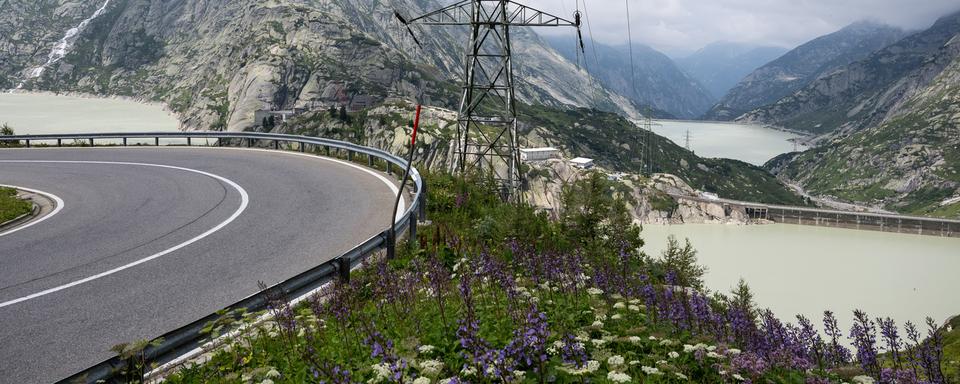 Des lignes électriques passent en aval des deux lacs de retenue du Grimsel, à l'avant, et du Raetterichs Boden, le mercredi 27 juillet 2022, au Grimsel. [Keystone - Peter Schneider]