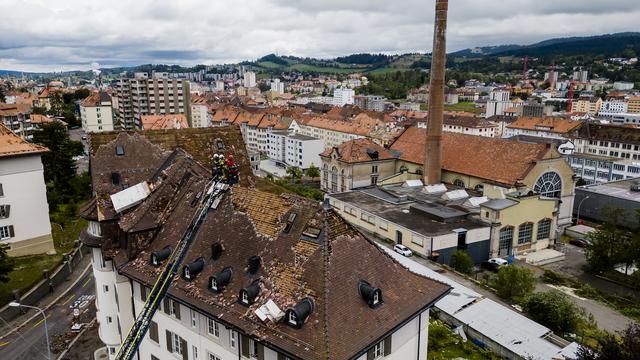 Des pompiers observent les dégâts de la tempête à La Chaux-de-Fonds. [Keystone - Jean-Christophe Bott]