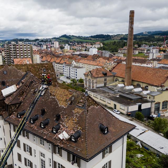 Des pompiers observent les dégâts de la tempête à La Chaux-de-Fonds. [Keystone - Jean-Christophe Bott]