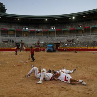 Des fêtards se reposent dans l'arène des taureaux après une corrida de la fête de San Fermin à Pampelune, en Espagne, jeudi 9 juillet 2015. [Keystone - AP Photo/Daniel Ochoa de Olza]