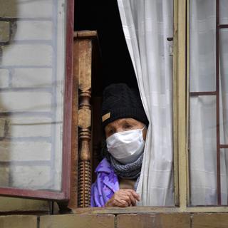 Une personne âgée regarde par la fenêtre dans le quartier de Kennedy, une des zones de Bogota qui connaît un grand nombre de contaminations au Covid-19. Colombie, le 3 juin 2020. [AFP - Raul Arboleda]