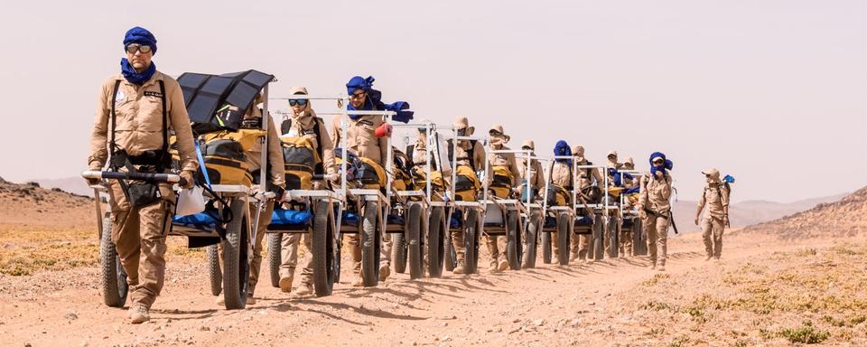 Dans le désert, chaque climatonaute tire un chariot sur lequel il y a notamment sa réserve d'eau pour la journée: huit litres en tout et pour tout. Réserve naturelle du roi Salman bin Abdulaziz, Arabie Saoudite, mai 2023. [Human Adaptation Institute - Lucas Santucci]