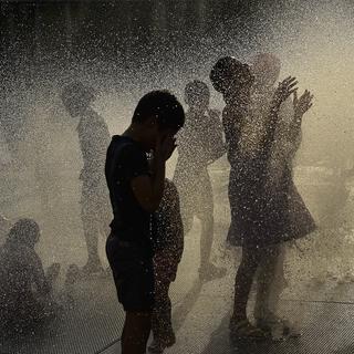 Des enfants jouant dans une fontaine à eau, au nord de l'Espagne à Pampelune. [Keystone/AP Photo - Alvaro Barrientos]