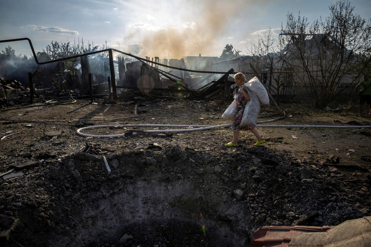 Une femme locale passe devant le cratère d'un impact après une frappe russe sur une zone résidentielle de Pokrovsk (est), le 3 août 2024. [REUTERS - Thomas Peter]