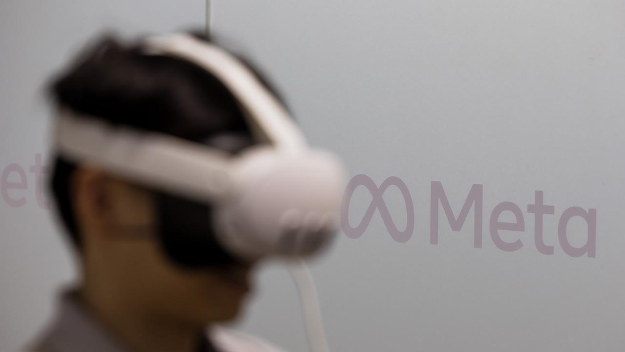 Un homme coiffé d'un casque de "réalité virtuelle" dans un stand de l'entreprise Meta. [Keystone/EPA - Alex Plavevski]