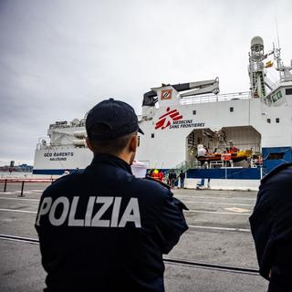 Des policiers italiens devant le Geo Barents, un navire de sauvetage de migrants exploité par Médecins sans frontières, autorisé à accoster dans le port de Gênes. [AFP - Mauro Ujetto]
