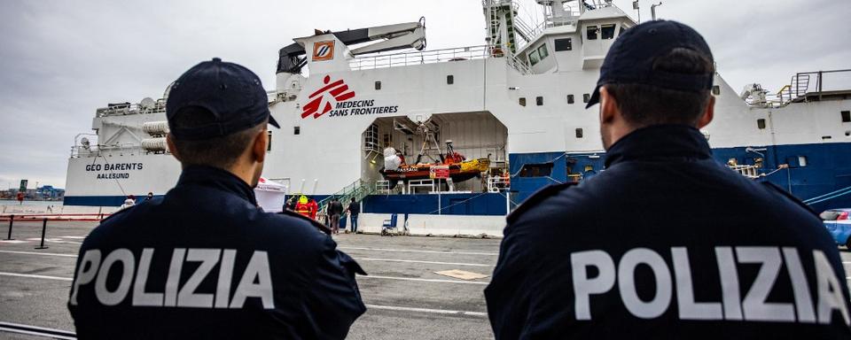 Des policiers italiens devant le Geo Barents, un navire de sauvetage de migrants exploité par Médecins sans frontières, autorisé à accoster dans le port de Gênes. [AFP - Mauro Ujetto]