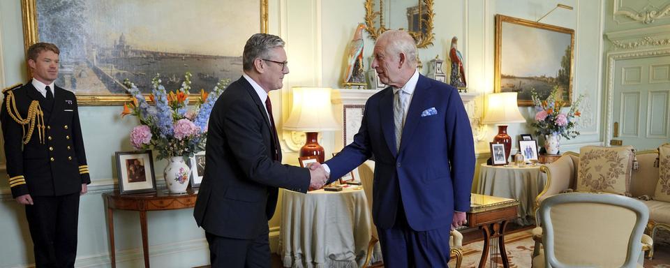 Le roi Charles III de Grande-Bretagne, à droite, serre la main de Keir Starmer après avoir invité le chef du Parti travailliste à devenir premier ministre et à former un nouveau gouvernement, le vendredi 5 juillet 2024. [Pool Photo via AP - Keystone - Yui Mok]