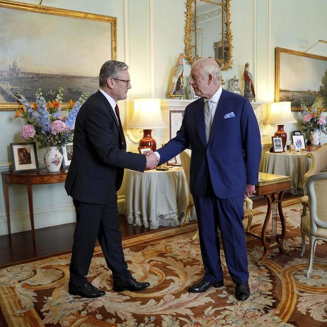 Le roi Charles III de Grande-Bretagne, à droite, serre la main de Keir Starmer après avoir invité le chef du Parti travailliste à devenir premier ministre et à former un nouveau gouvernement, le vendredi 5 juillet 2024. [Pool Photo via AP - Keystone - Yui Mok]