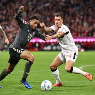 Jamal Musiala en action contre Granit Xhaka, lors du match entre le Bayern Munich et le Bayer Leverkusen. [Keystone - EPA/ANNA SZILAGYI]