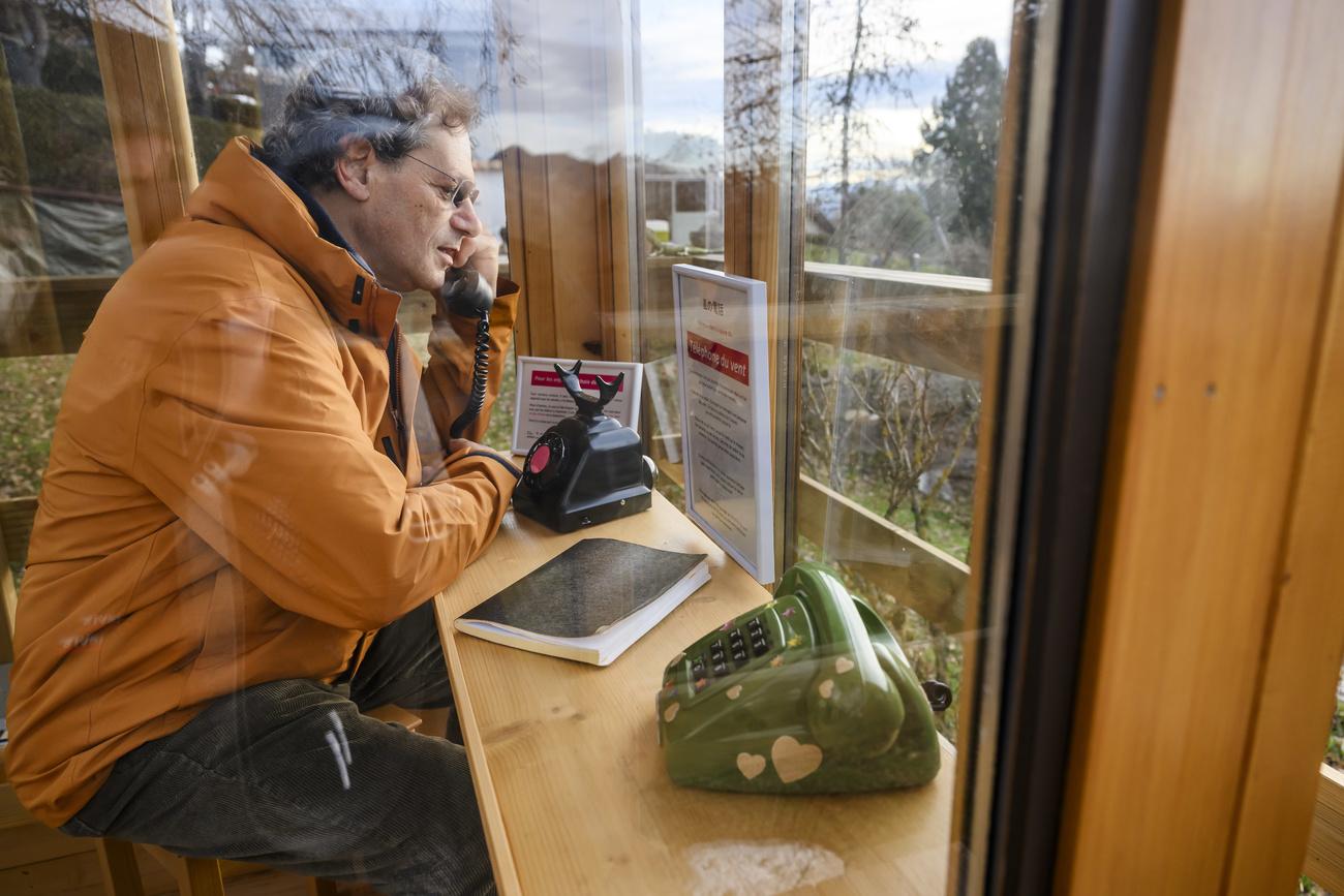 Le "téléphone du vent" de Villars-Burquin (VD) est une cabine vitrée en bois dans laquelle deux téléphones non-branchés sont posés avec deux tabourets et un carnet. [KEYSTONE - JEAN-CHRISTOPHE BOTT]