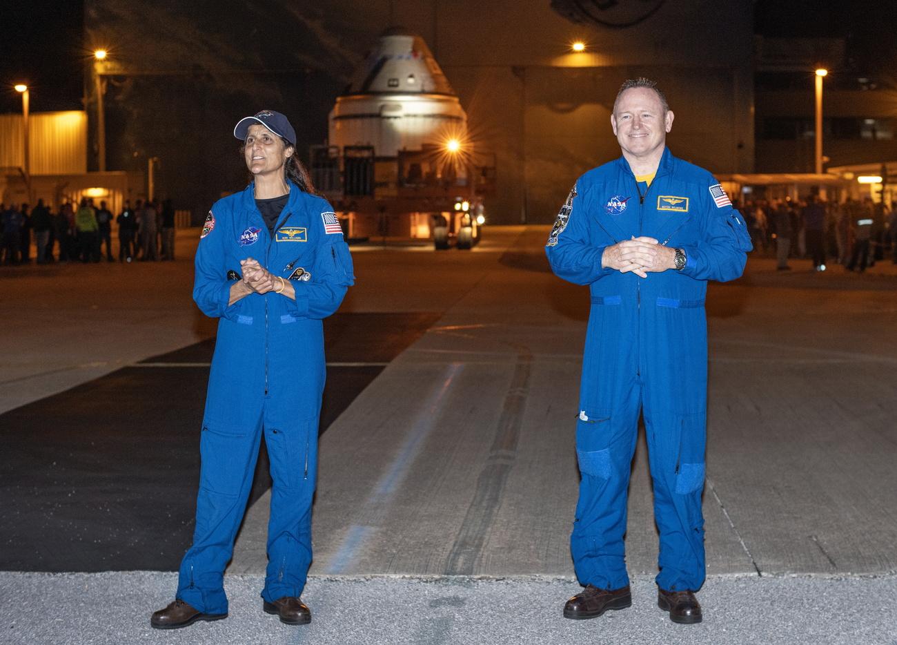 Les astronautes de la NASA Suni Williams (à gauche) et Butch Wilmore (à droite) se tiennent devant le vaisseau spatial Boeing CST-100 Starliner lors de la sortie du vaisseau de l'usine de production Boeing du Centre spatial Kennedy vers le complexe de lancement spatial-41 de la station spatiale de Cap Canaveral en Floride, le 16 avril 2024. [Keystone - Cristobal Herrera-Ulashkevich]
