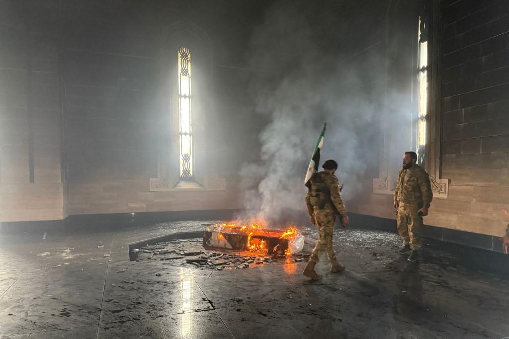 Des rebelles se tiennent à côté du tombeau en feu de l'ancien président Hafez al-Assad. [AFP - AAREF WATAD]