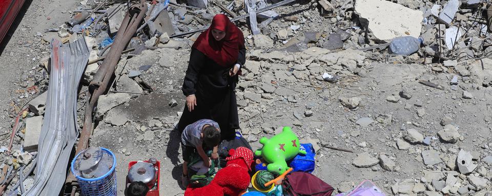 Une femme et ses enfants avec leurs affaires près de jouets récupérés après un tir israélien qui a détruit leur maison dans le village Aita al-Shaab au Liban. [Keystone/AP Photo - Mohammed Zaatari]