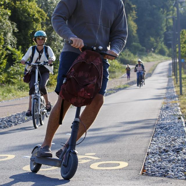 Une personne à trottinette et des cyclistes utilisent la Voie verte du CEVA (Cornavin-Eaux-Vives-Annemasse), le 29 juillet 2019 à Genève. [Keystone - Salvatore Di Nolfi]