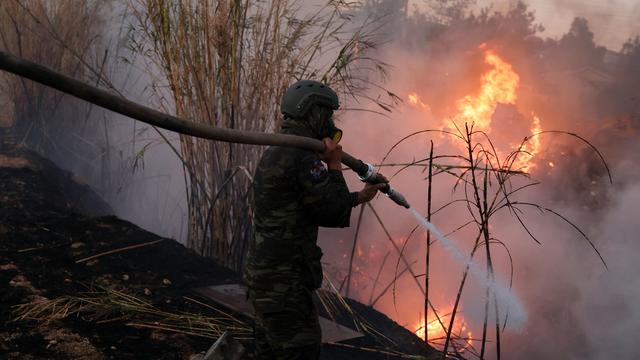 Une personne de la brigade des pompiers face à l'incendie qui ravage la forêt de Nea Penteli aux portes d'Athènes. [AFP - Costas Baltas]