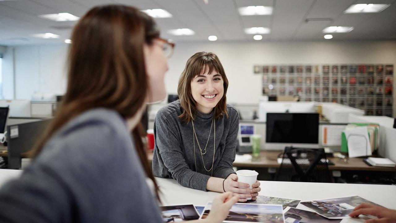 Deux femmes assises dans un bureau discutent et rient. [Mint Images via AFP - Mint Images]