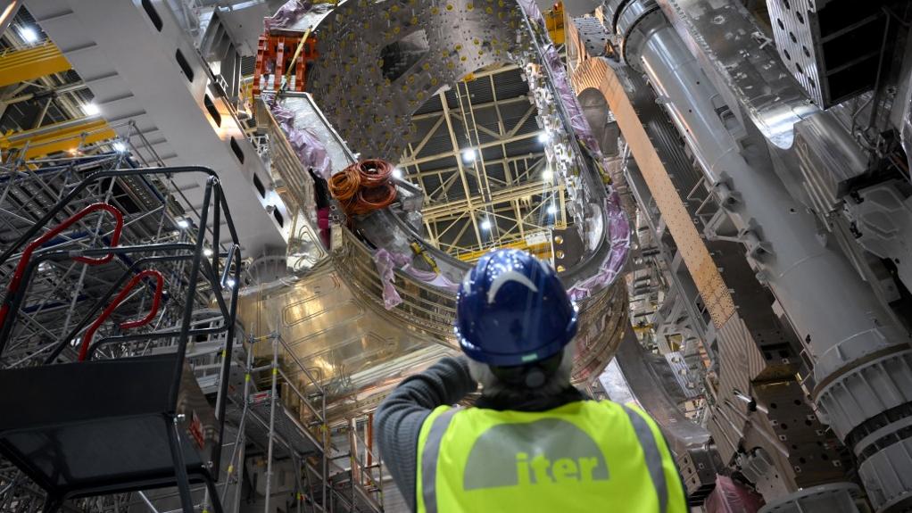 Un homme prend une photo d'un module en cours d'assemblage dans le cadre du projet international de fusion nucléaire Iter à Saint-Paul-les-Durance, dans le sud de la France, le 5 janvier 2023. [AFP - Nicolas Tucat]