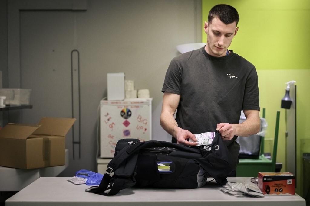 Rémy, travailleur social, prépare son sac avec des pipes à crack propres, de l'eau et des barres énergétiques avant de patrouiller près de la salle d'injection sécurisée du Quai 9. Genève, le 8 décembre 2023. [AFP - GABRIEL MONNET]