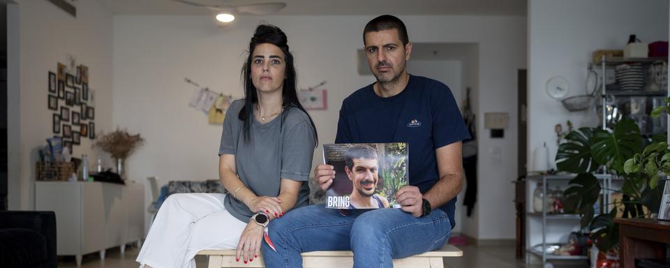 Hila Levy, sitting beside her husband Michael, holds up a portrait of his brother, 33-year-old Or Levy, in the family house in Ganei Tikva, Israel, Sunday, Oct. 29, 2023. Or Levy, an Israeli citizen, was abducted by Hamas militants from the "Nova" Music Festival near Kibbutz Re'im, during the group's unprecedented attack on Oct. 7 that resulted in the killing over 1,400 people and abduction of over 220. (AP Photo/Ohad Zwigenberg) [AP Photo - Ohad Zwigenberg]