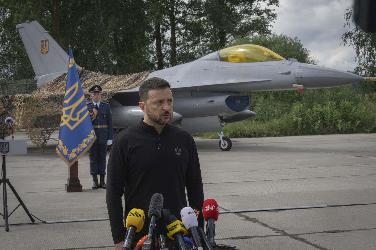 Le président ukrainien Volodymyr Zelenskyy devant des avions de combat F-16 de l'armée de l'air ukrainienne. [KEYSTONE - EFREM LUKATSKY]