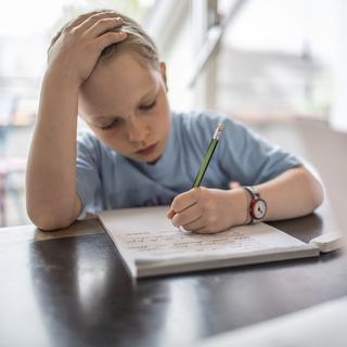 Un enfant qui suit l'école à la maison. [Keystone - Gaetan Bally]