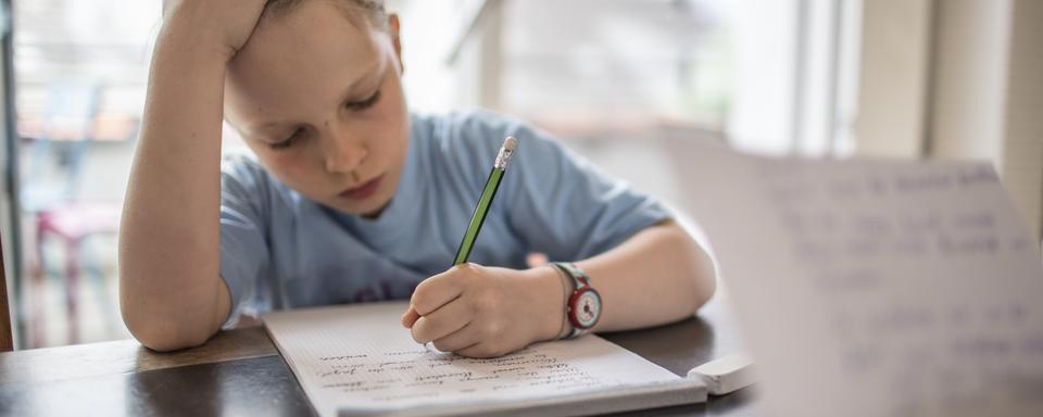 Un enfant qui suit l'école à la maison. [Keystone - Gaetan Bally]