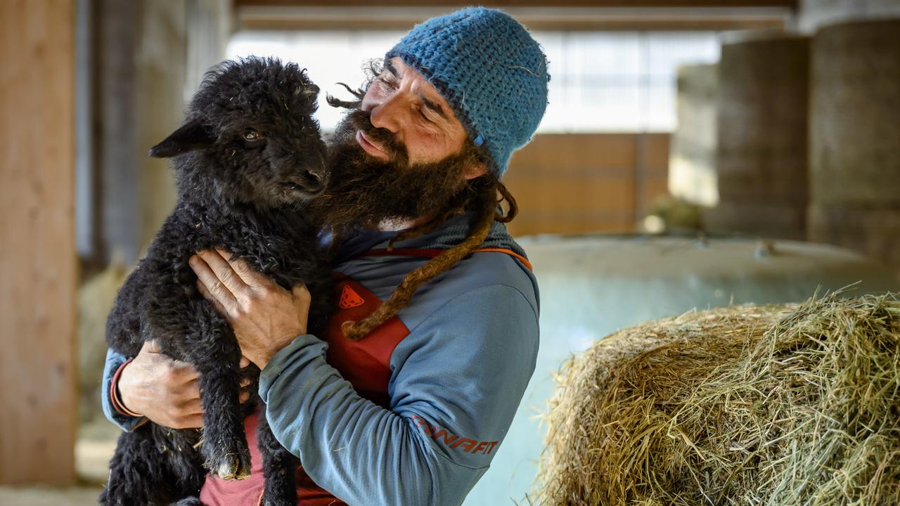Damien Jeannerat pose avec "Zelda", un agneau de la bergerie de Naye. [Keystone - Jean-Christophe Bott]