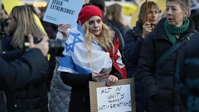 Une manifestante arbore un drapeau israélien et une pancarte "Agissons ensemble contre l'antisémitisme" lors d'un rassemblement à Zurich. [KEYSTONE - WALTER BIERI]