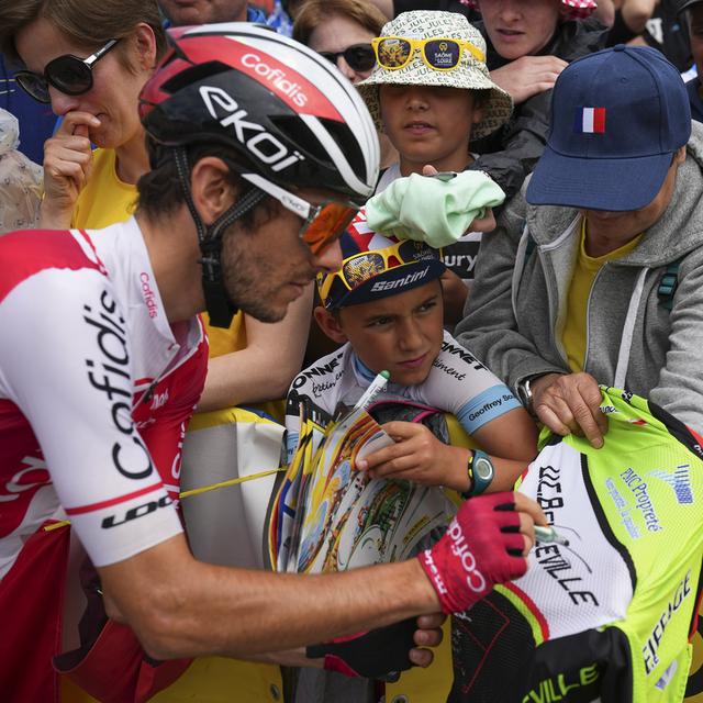 Des jeunes fans de cyclisme demandent des autographes aux coureurs du Tour de France. [Keystoone/AP Photo - Daniel Cole]