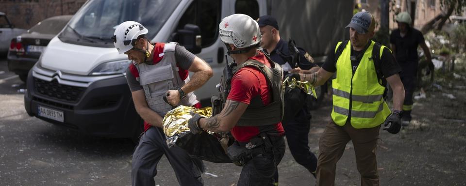 Des sauveteurs après l'attaque de missiles sur Kiev. [Keystone - Alex Babenko/AP]