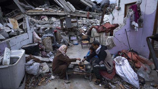 Une famille dans les ruines de sa maison à Rafah. [Keystone - AP Photo/Fatima Shbair]