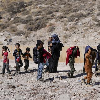 Plusieurs familles fuient le Liban à pieds vers la Syrie pour échapper à l'armée israélienne. [Keystone/AP Photo - Hassan Ammar]