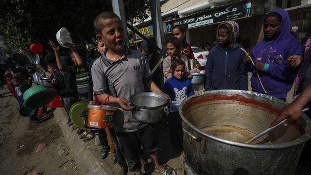 Des enfants palestiniens déplacés font la queue pour recevoir de la nourriture fournie par des donateurs arabes et palestiniens dans la ville de Deir Al Balah, au sud de la bande de Gaza, le 24 février 2024. [Keystone - EPA/MOHAMMED SABER]