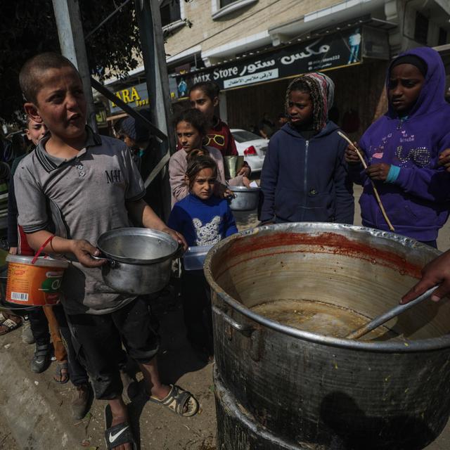 Des enfants palestiniens déplacés font la queue pour recevoir de la nourriture fournie par des donateurs arabes et palestiniens dans la ville de Deir Al Balah, au sud de la bande de Gaza, le 24 février 2024. [Keystone - EPA/MOHAMMED SABER]