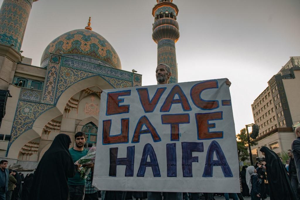 Un manifestant iranien tient une pancarte anti-israélienne, alors qu'il participe à un rassemblement de protestation pour condamner une frappe aérienne israélienne contre le quartier général du Hezbollah dans la banlieue de Beyrouth, et l'assassinat du secrétaire général du Hezbollah, Hassan Nasrallah. [Middle East Images via AFP - HOSSEIN BERIS]